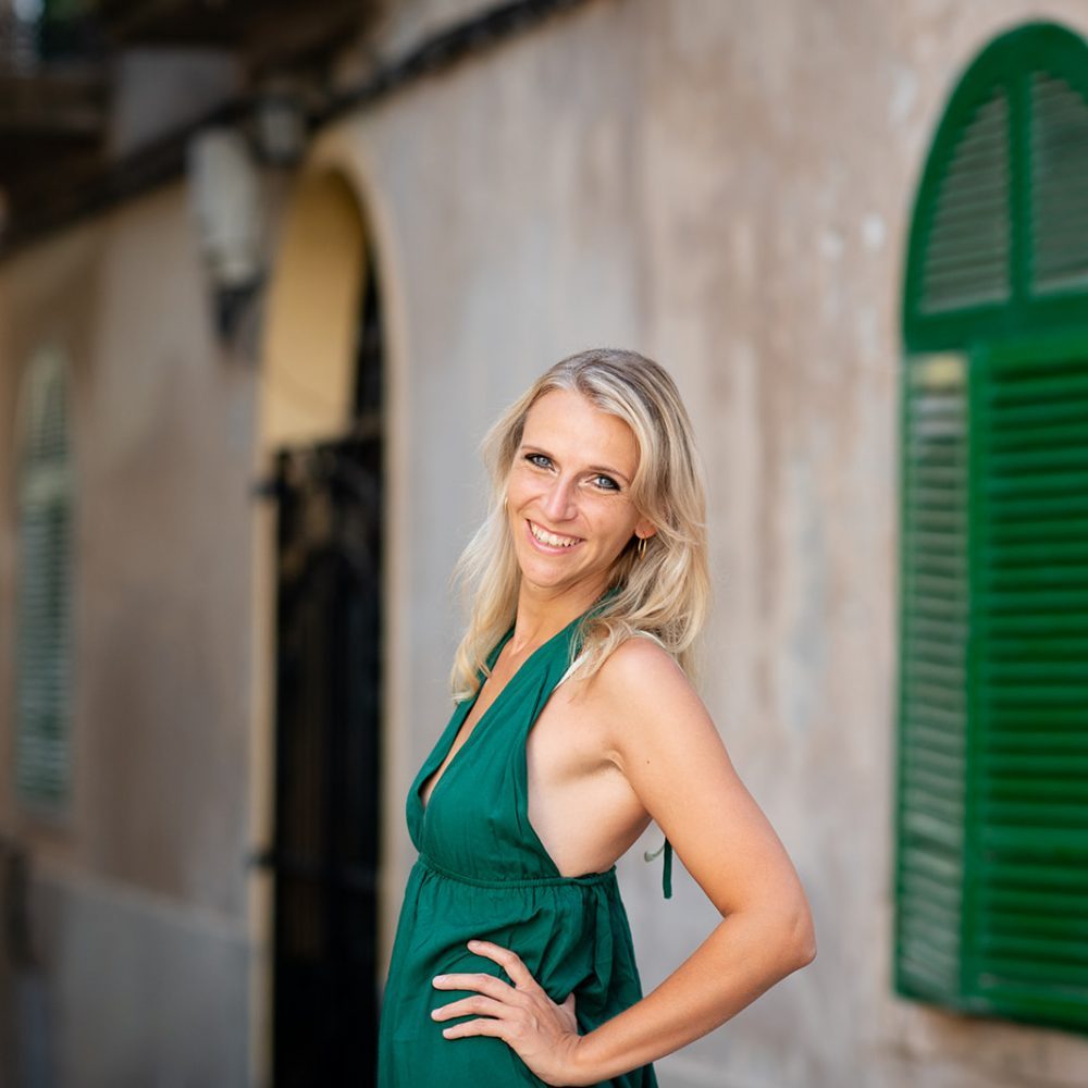 Nina Wassinger im grünen Kleid vor einer Hauswand mit grünen Fensterläden